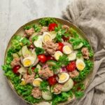 tuna salad vegetable salad with quail eggs lettuce red onion and cucumbers on a light gray table 1